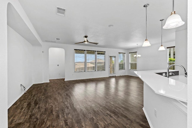 7604 Nunsland Dr, Austin, TX 78744 - unfurnished living room featuring arched walkways, a sink, wood finished floors, a ceiling fan, and a chandelier