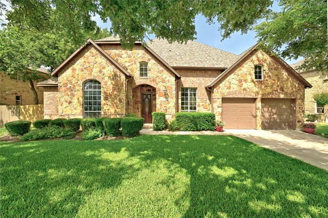 1607 Mesa Verde Dr, Round Rock, TX 78681 - french country style house with stone siding, concrete driveway, an attached garage, and roof with shingles