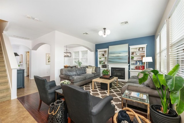 361 Stone View Trl, Austin, TX 78737 - living room featuring arched walkways, light tile patterned floors, a glass covered fireplace, and stairs