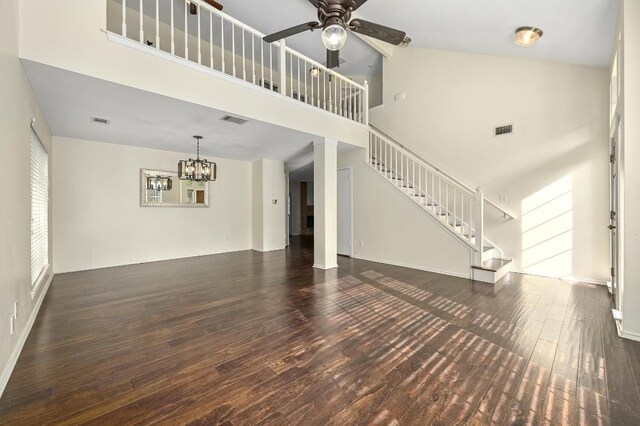 12400 Summersweet Cv, Austin, TX 78729 - unfurnished living room with wood finished floors, stairway, a ceiling fan, a towering ceiling, and a chandelier