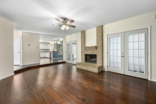 unfurnished living room with french doors, ceiling fan, dark wood finished floors, a brick fireplace, and baseboards
