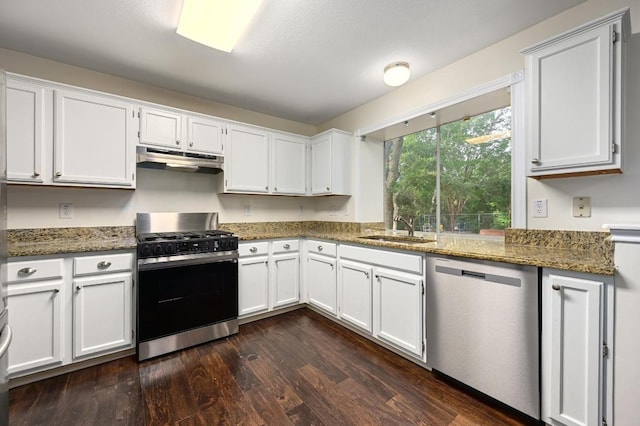 kitchen featuring stainless steel appliances, under cabinet range hood, a sink, white cabinets, and dark wood-style flooring