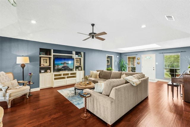 living room featuring ceiling fan, vaulted ceiling, dark wood finished floors, recessed lighting, and a skylight
