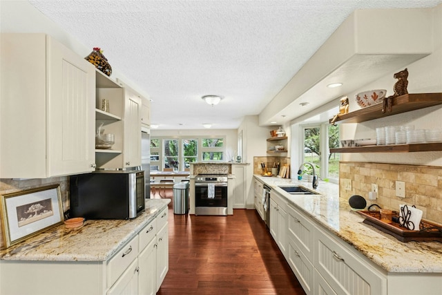 kitchen with open shelves, a sink, appliances with stainless steel finishes, dark wood-style flooring, and a textured ceiling