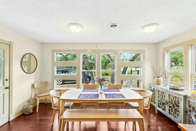 dining area with dark wood-type flooring, a textured ceiling, and baseboards