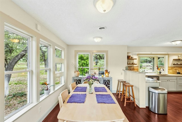 dining space featuring a textured ceiling, dark wood finished floors, and baseboards
