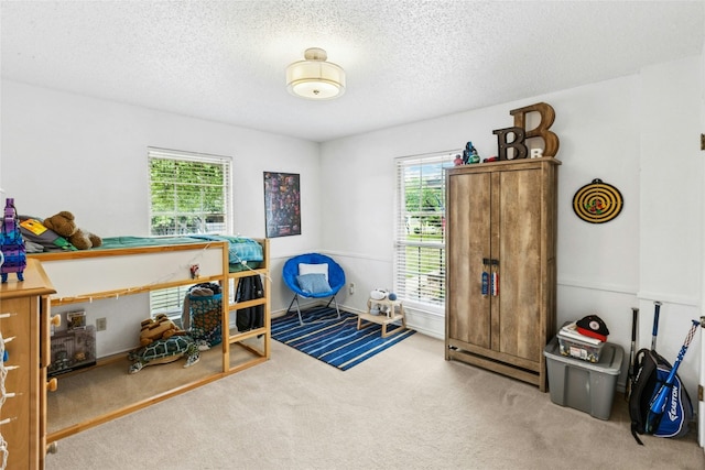 bedroom with multiple windows, carpet floors, and a textured ceiling