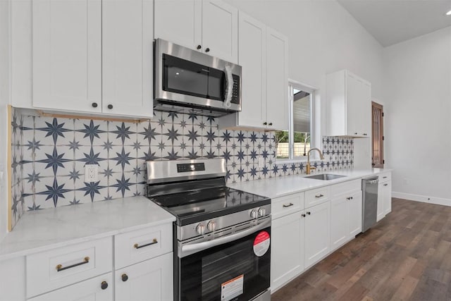 kitchen featuring stainless steel appliances, a sink, white cabinets, dark wood-style floors, and decorative backsplash