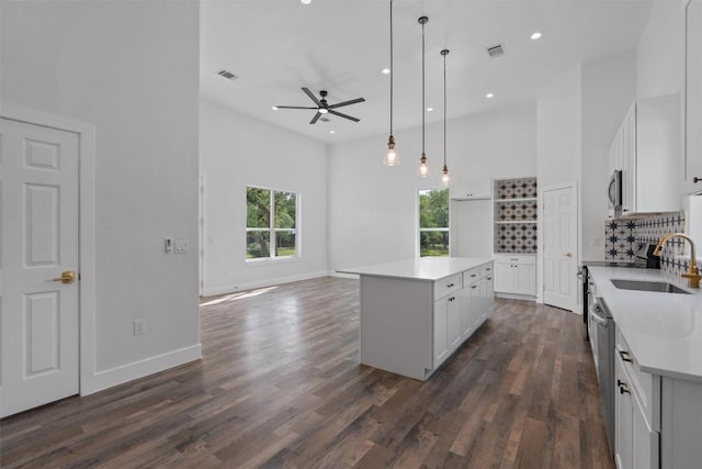 kitchen featuring a sink, a center island, a ceiling fan, a towering ceiling, and appliances with stainless steel finishes