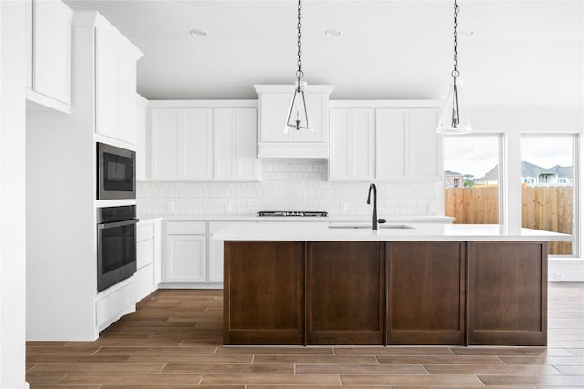 639 Bay Breeze Dr, Kyle, TX 78640 - kitchen with stainless steel oven, a sink, wood tiled floors, built in microwave, and light countertops