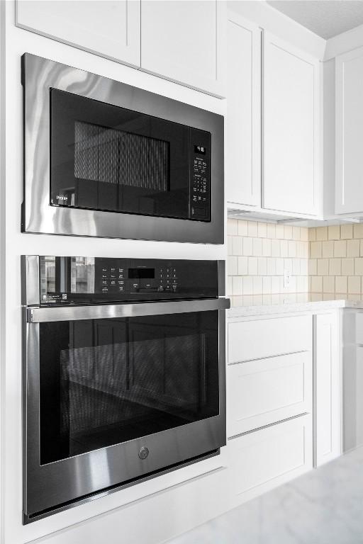 639 Bay Breeze Dr, Kyle, TX 78640 - kitchen view of built in microwave, stainless steel oven, white cabinets, light countertops, and decorative backsplash