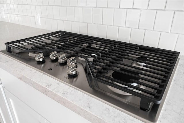 639 Bay Breeze Dr, Kyle, TX 78640 - kitchen view of stainless steel gas cooktop, decorative backsplash, white cabinets, and light countertops