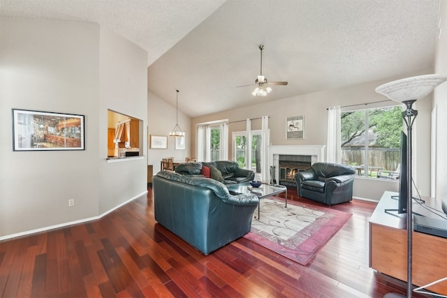 living room featuring ceiling fan, wood finished floors, a fireplace, a textured ceiling, and high vaulted ceiling