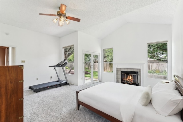 bedroom featuring access to outside, multiple windows, carpet flooring, a tiled fireplace, and lofted ceiling