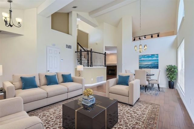 living room featuring a chandelier, high vaulted ceiling, wood finished floors, beamed ceiling, and baseboards
