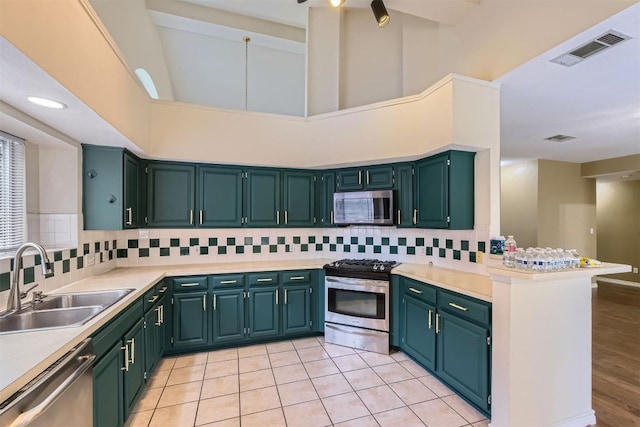 kitchen with appliances with stainless steel finishes, a sink, backsplash, and light countertops