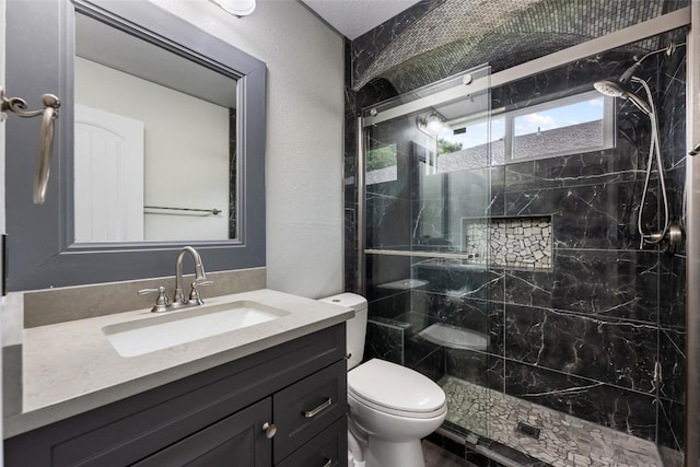 full bathroom with toilet, vanity, a marble finish shower, and a textured wall
