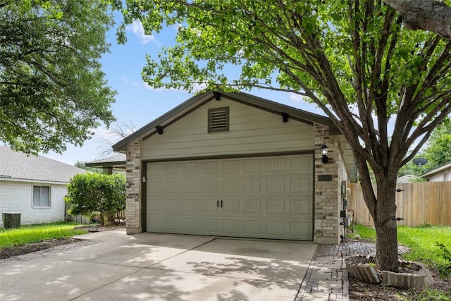 garage with concrete driveway and fence