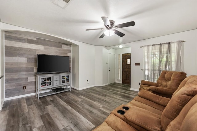 living area with ceiling fan, baseboards, and dark wood-type flooring