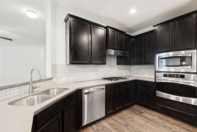 503 S Meadowlark St Unit B, Lakeway, TX 78734 - kitchen with appliances with stainless steel finishes, a sink, under cabinet range hood, backsplash, and light wood finished floors