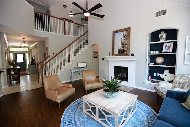 1401 Brixey Cv, Austin, TX 78754 - living room featuring a towering ceiling, a ceiling fan, wood finished floors, stairway, and built in shelves