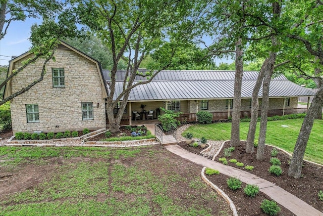 3301 Arrowhead Cir, Round Rock, TX 78681 - back of house with covered porch, a gambrel roof, a lawn, stone siding, and a metal roof