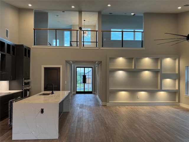 3318 Bay W Blvd, Horseshoe Bay, TX 78657 - kitchen featuring dark wood-type flooring, ceiling fan, stainless steel double oven, a kitchen island with sink, and a high ceiling