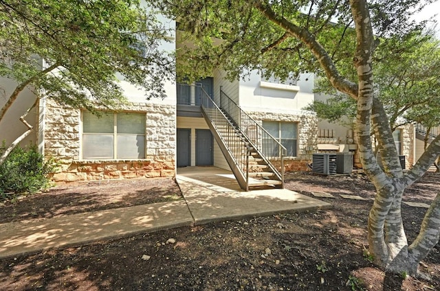 6000 Shepherd Mountain Cv Unit 107, Austin, TX 78730 - rear view of house with central AC unit, stairway, a patio, and stone siding