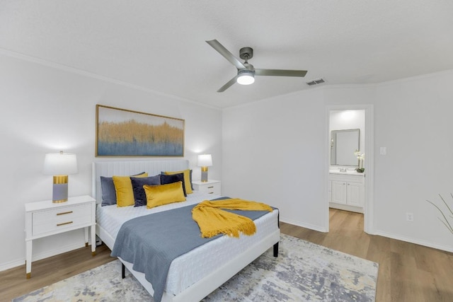 bedroom featuring wood finished floors, ornamental molding, baseboards, connected bathroom, and a ceiling fan