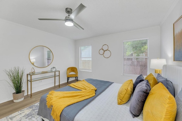 bedroom with multiple windows, wood finished floors, ornamental molding, ceiling fan, and baseboards