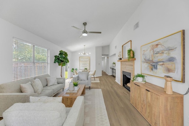 5901 Jacob Gln, Austin, TX 78727 - living area with light wood-type flooring, vaulted ceiling, a fireplace, ceiling fan, and a chandelier