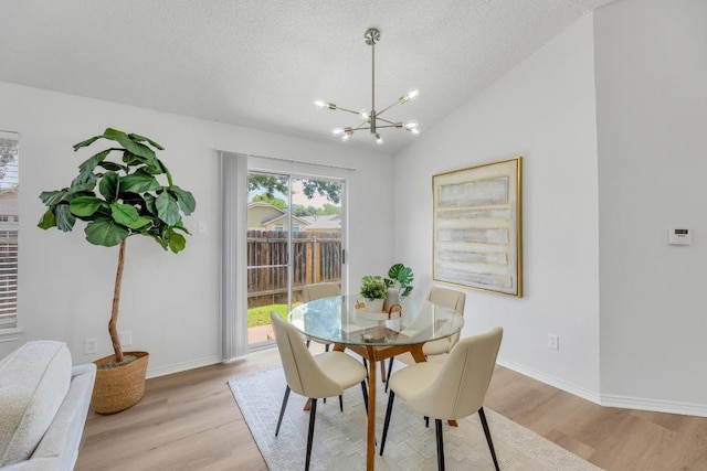 5901 Jacob Gln, Austin, TX 78727 - dining space featuring light wood-style flooring, a chandelier, a textured ceiling, baseboards, and vaulted ceiling