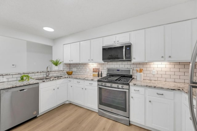 5901 Jacob Gln, Austin, TX 78727 - kitchen featuring stainless steel appliances, a sink, white cabinetry, and backsplash