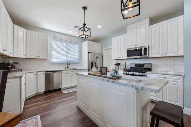 kitchen with appliances with stainless steel finishes, a sink, backsplash, a kitchen island, and recessed lighting