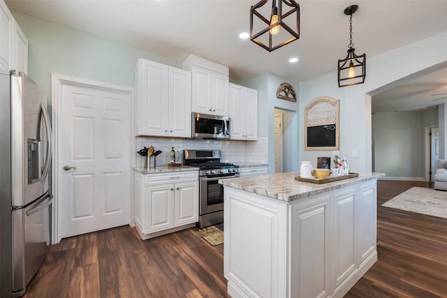 kitchen featuring appliances with stainless steel finishes, dark wood finished floors, white cabinetry, tasteful backsplash, and a center island