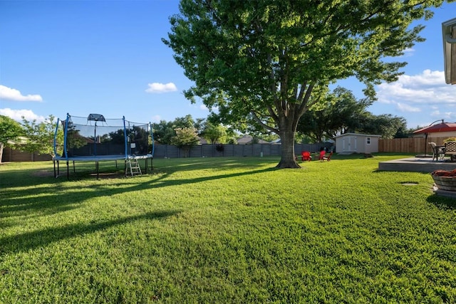 view of yard with a trampoline, a storage unit, and an outdoor structure