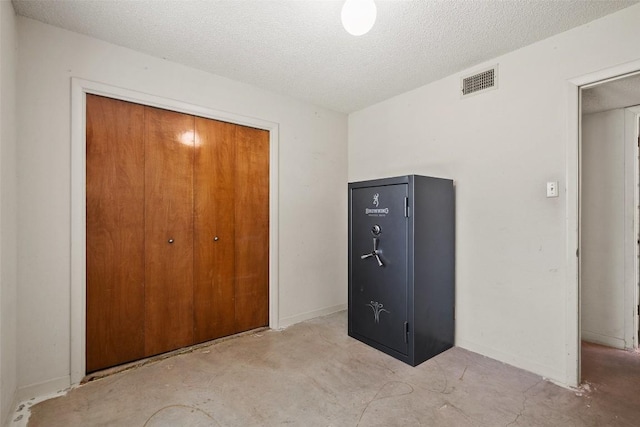 unfurnished bedroom featuring unfinished concrete flooring, a closet, and a textured ceiling
