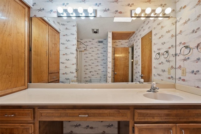 full bathroom with wallpapered walls, vanity, and a shower