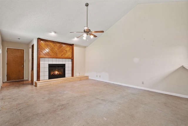 unfurnished living room featuring vaulted ceiling, a tile fireplace, a ceiling fan, concrete flooring, and baseboards