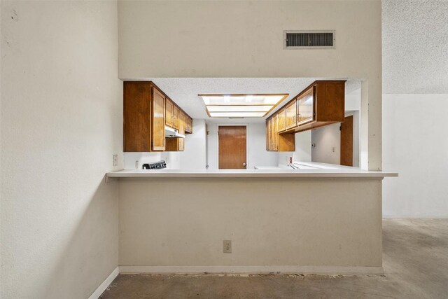 3317 William Cannon Dr Unit A, Austin, TX 78745 - kitchen featuring concrete floors, under cabinet range hood, a peninsula, and light countertops