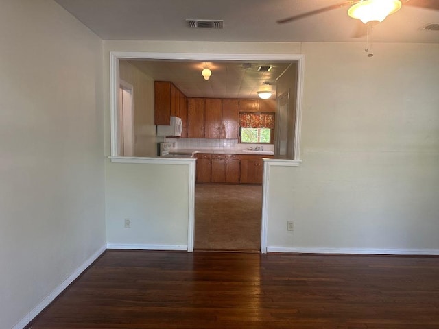 762 E Walnut St, La Grange, TX 78945 - kitchen featuring brown cabinets, white microwave, wood finished floors, decorative backsplash, and light countertops