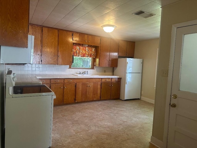 762 E Walnut St, La Grange, TX 78945 - kitchen featuring freestanding refrigerator, stove, brown cabinets, a sink, and backsplash