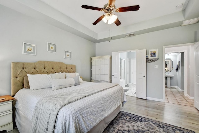 410 Easton Dr, San Marcos, TX 78666 - bedroom featuring wood finished floors, a tray ceiling, baseboards, ensuite bath, and a sink