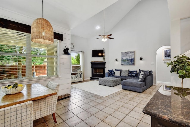 410 Easton Dr, San Marcos, TX 78666 - living room with a fireplace with raised hearth, light tile patterned flooring, a ceiling fan, arched walkways, and high vaulted ceiling