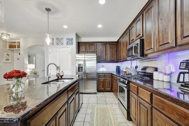 410 Easton Dr, San Marcos, TX 78666 - kitchen with appliances with stainless steel finishes, a sink, dark stone counters, arched walkways, and light tile patterned floors