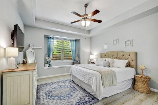 410 Easton Dr, San Marcos, TX 78666 - bedroom with light wood finished floors, baseboards, a tray ceiling, and a ceiling fan
