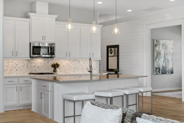 716 Dayridge Dr, Dripping Springs, TX 78620 - kitchen with stainless steel microwave, backsplash, white cabinets, a sink, and baseboards