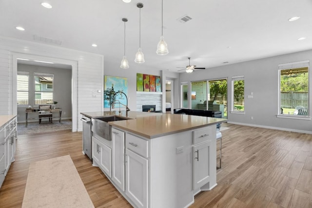 716 Dayridge Dr, Dripping Springs, TX 78620 - kitchen featuring a sink, a lit fireplace, a ceiling fan, light wood-style flooring, and recessed lighting