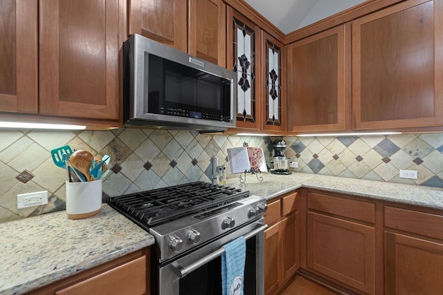 11036 Cherisse Dr, Austin, TX 78739 - kitchen with appliances with stainless steel finishes, light stone counters, and brown cabinetry