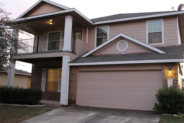 view of front facade featuring brick siding, a balcony, driveway, and a garage